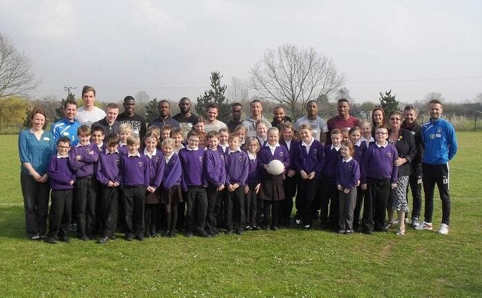 Milldene Primary School pupils with Colchester United footballers on the school field