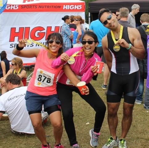 Three triathlon finishers biting their medals
