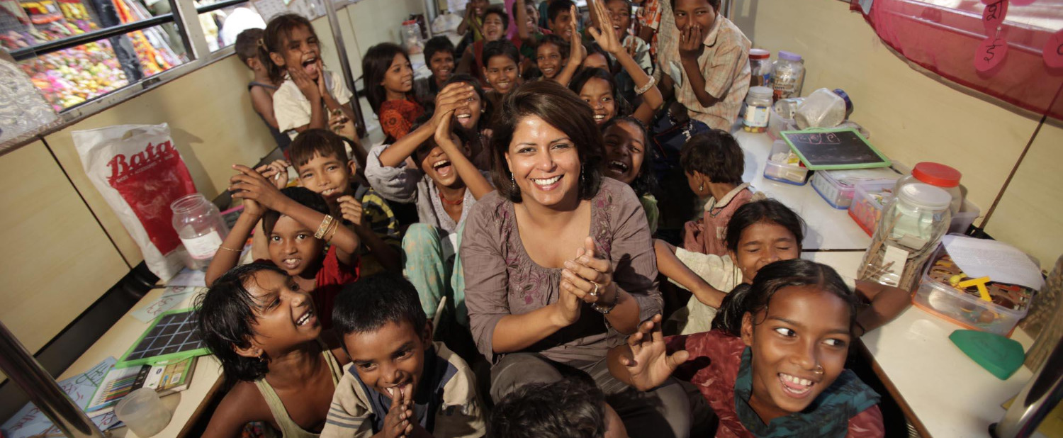Founder Seema Sharma clapping with a busload of laughing children inside the School on Wheels classroom