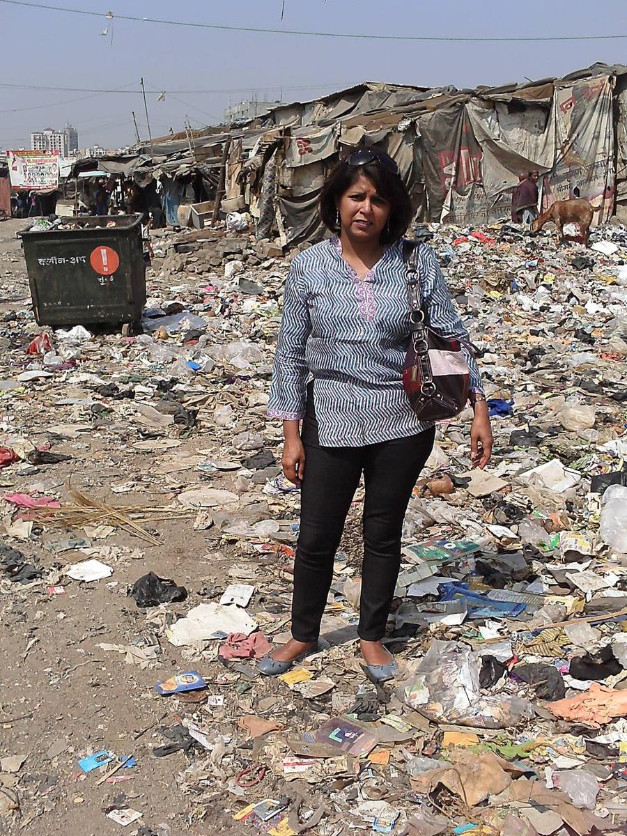Founder Seema Sharma standing on a rubbish-strewn street in a Mumbai slum